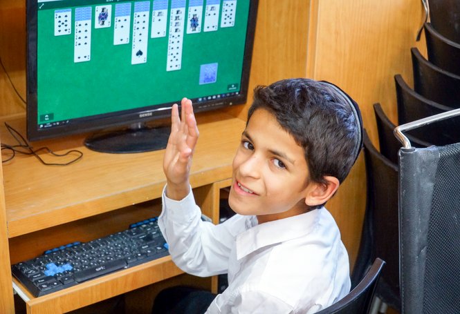 A Zion boy enjoying a card game on one of the tens of computers in use on campus.