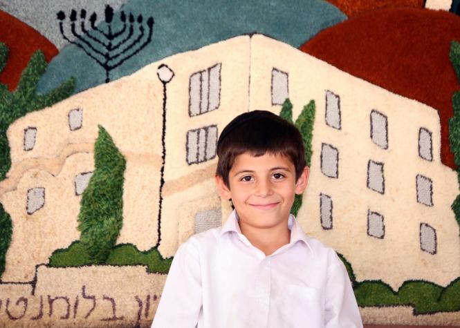 In the background of this smiling Zion boy is a carpet mural of the Zion Orphanage building.  