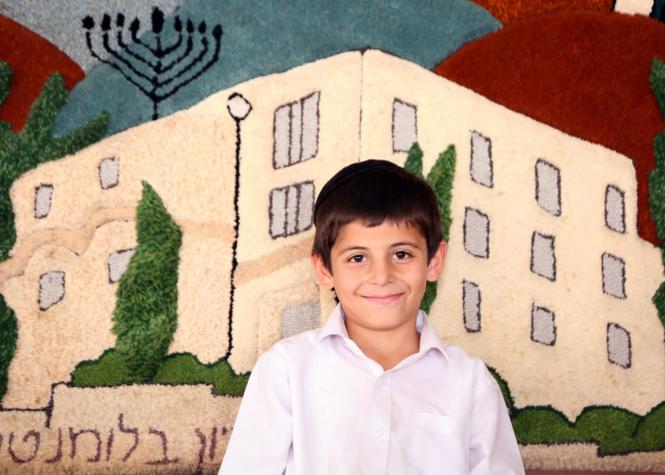 In the background of this smiling Zion boy is a carpet mural of the Zion Orphanage building.